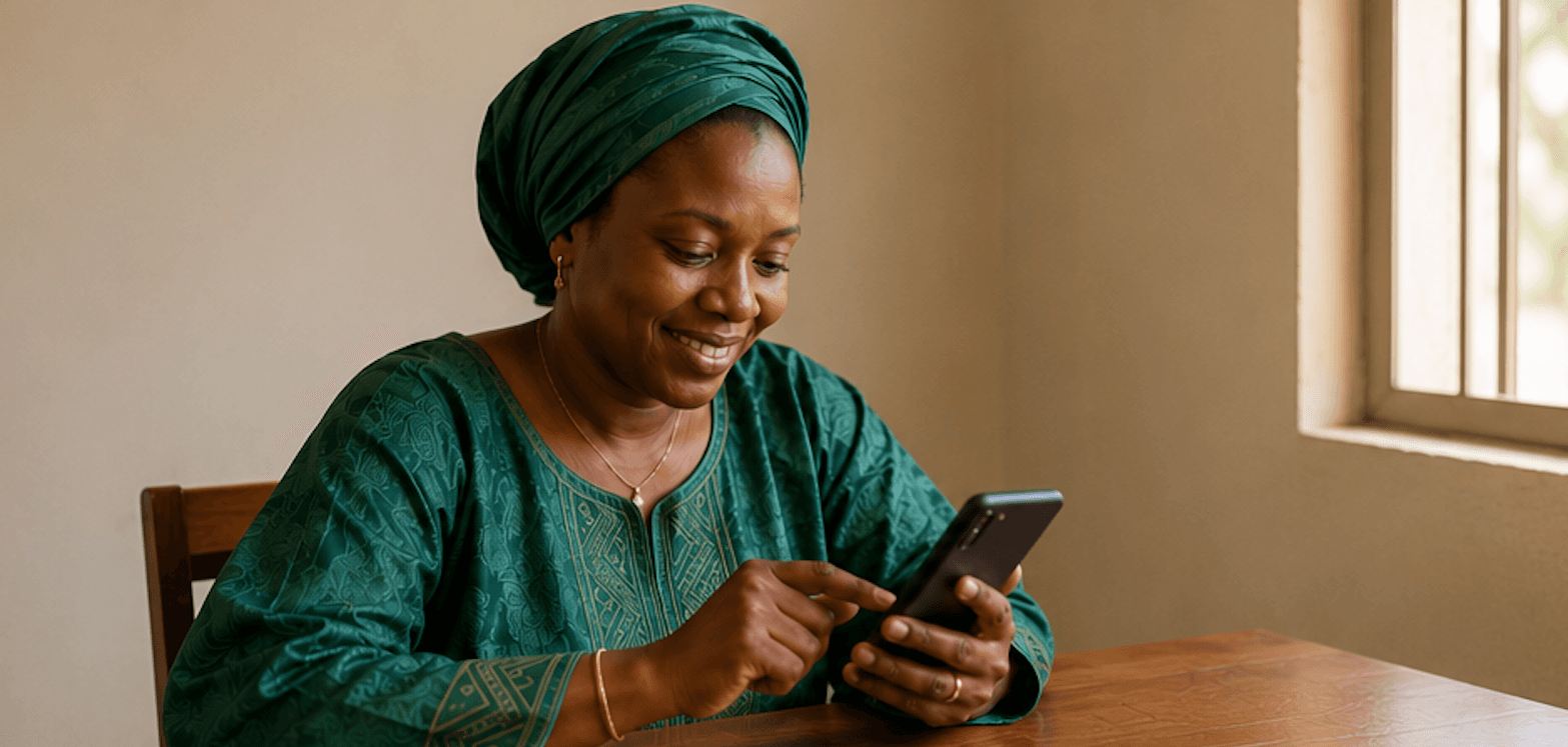 Une femme consulte sa tontine am am sur son téléphone, chez elle.